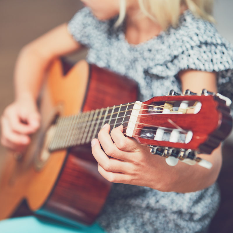 tyttö soittaa kitaraa musiikki tunnilla